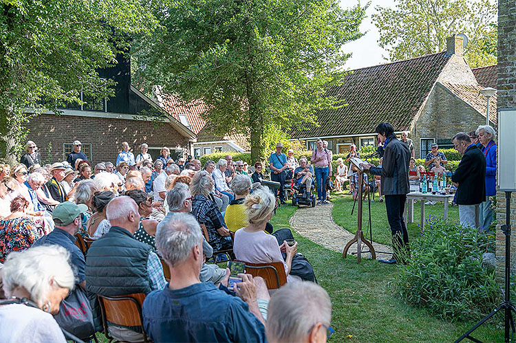 Bij de 20e herdenking 15-8-2025. Haas leest uit werk van Reve. Op de achtergrond Huize het Gras. Foto: Hans Nooitgedagt